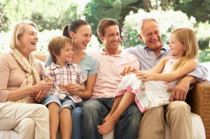 Three Generation Family Sitting On Sofa Together