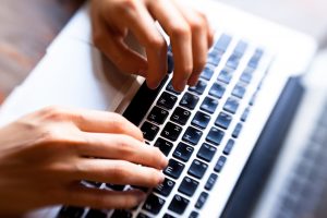 Hands typing on computer keyboard